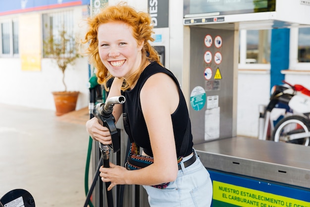 Donna divertendosi con la pistola di riempimento e sorridendo guardando la fotocamera