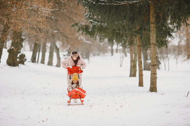 Donna e bambina in un parco con la slitta