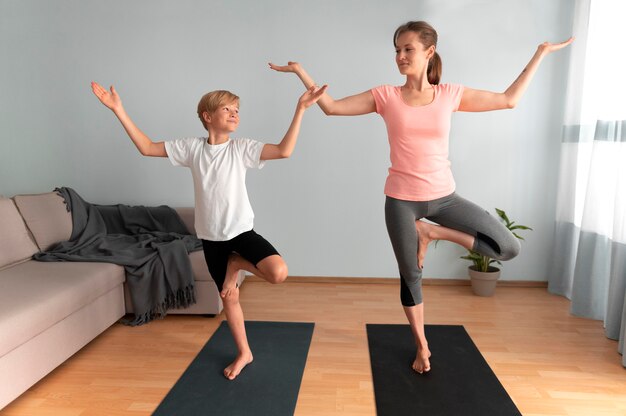 Donna e bambino a tutto campo che fanno yoga