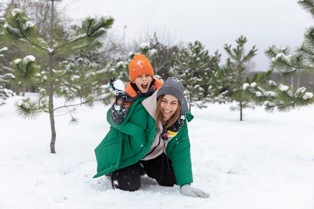 Donna e bambino a tutto campo che giocano con la neve