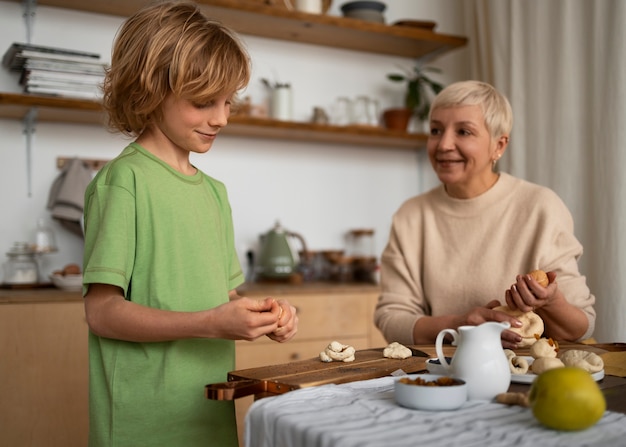 Donna e bambino del colpo medio che preparano alimento