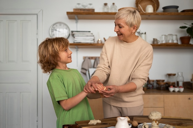 Donna e bambino del colpo medio che preparano alimento