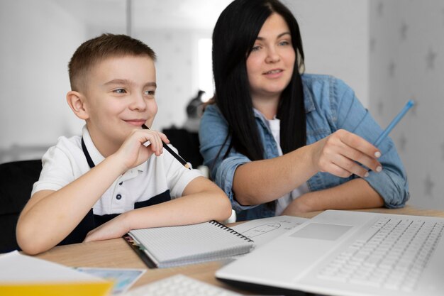 Donna e bambino di smiley del colpo medio con il computer portatile