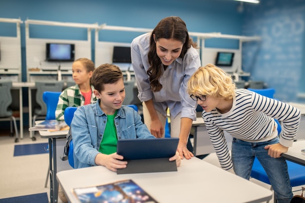 Donna e due studenti che esaminano tablet