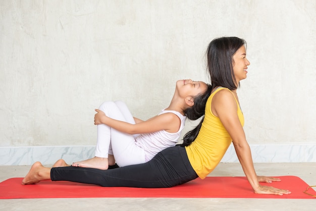 Donna e la sua piccola figlia affascinante che fa yoga