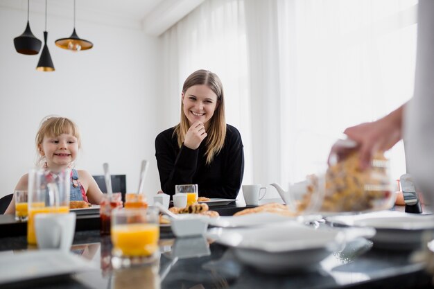 Donna e ragazza che esaminano l&#39;uomo delle colture che cucina la colazione