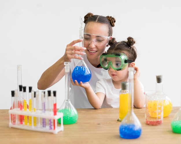 Donna e ragazza con gli occhiali di protezione che controllano esperimento