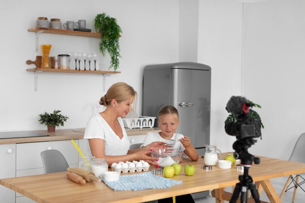 Donna e ragazza del tiro medio che cucinano insieme