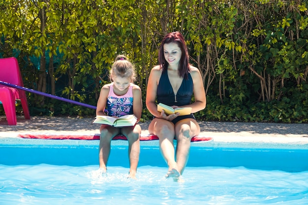 Donna e ragazza seduta a lettura piscina