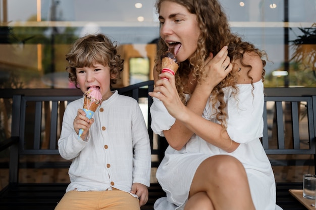 Donna e ragazzo del colpo medio che leccano i coni gelato