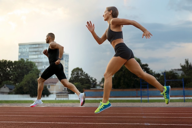 Donna e uomo che corre sulla pista vista laterale