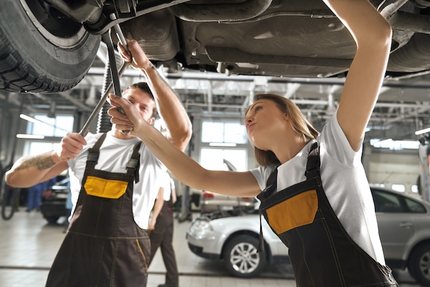 Donna e uomo che lavorano in autoservice come meccanici.