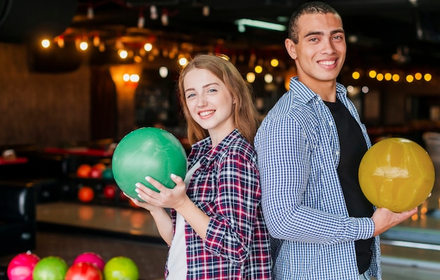 Donna e uomo che tengono le palle da bowling colorate