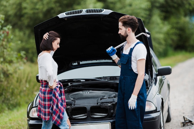 Donna e uomo con cofano auto aperto