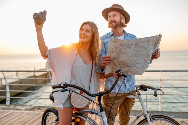 Donna e uomo innamorato che viaggiano in bicicletta al tramonto sul mare