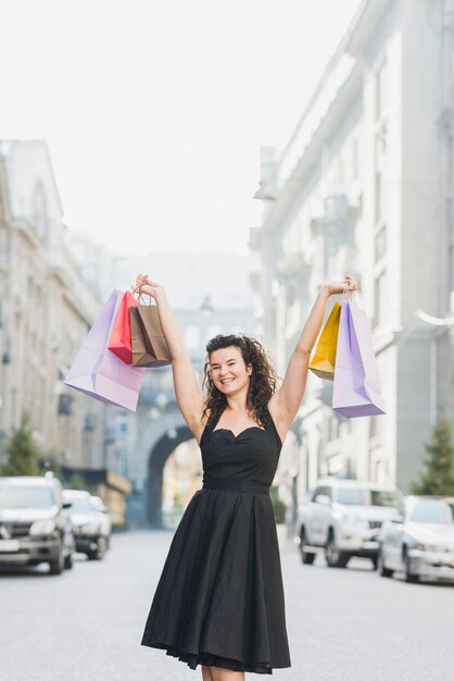Donna eccitata che alza le sue braccia con multi colorate borse per la spesa
