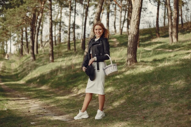 Donna elegante in un cappello nero in una foresta di primavera