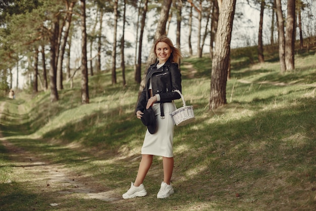 Donna elegante in un cappello nero in una foresta di primavera