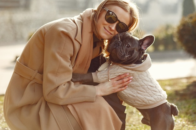 Donna elegante in un cappotto marrone con bulldog nero