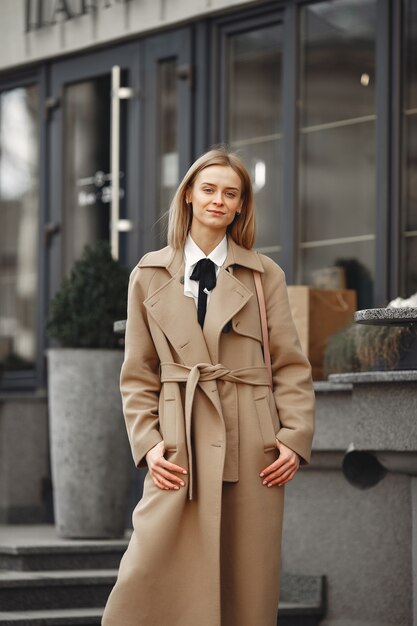 Donna elegante in un cappotto marrone in una città di primavera