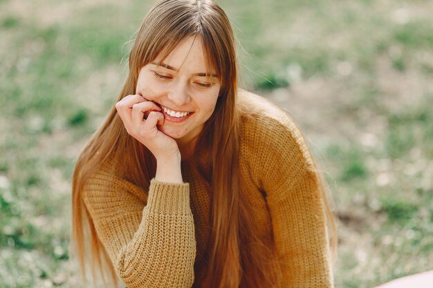 Donna elegante in un maglione marrone in un parco di primavera