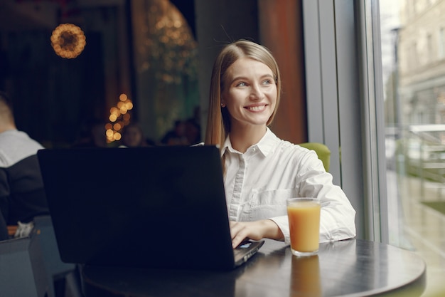 Donna elegante in una camicetta bianca che lavora in un caffè