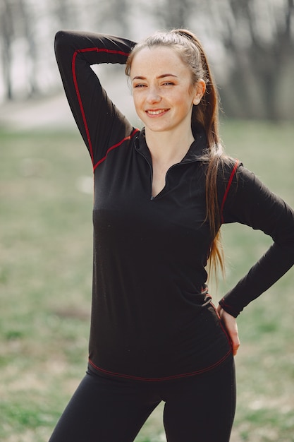 Donna elegante in vestiti neri in un parco di primavera