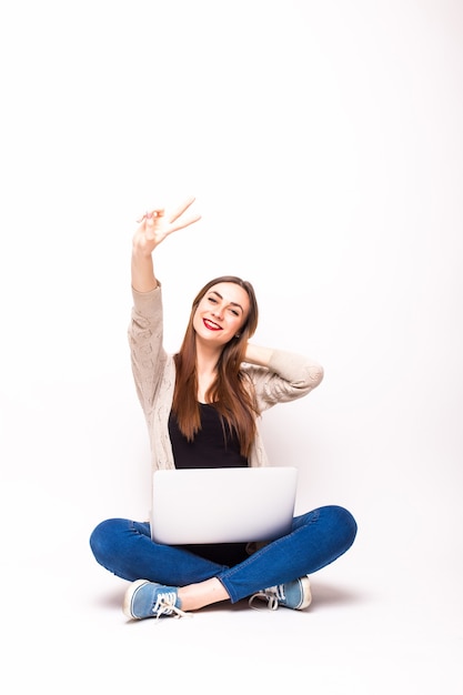 Donna emozionante con il computer portatile che gode del successo su bianco