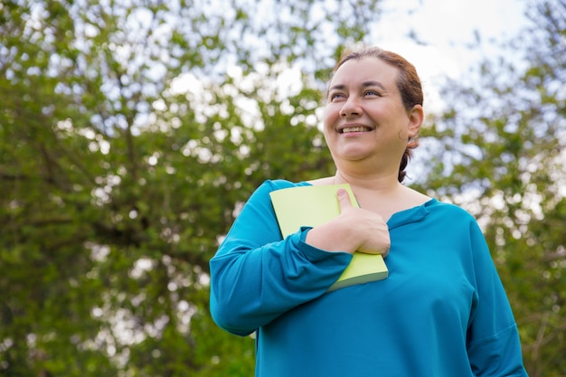 Donna emozionante sorridente colpita con la storia del libro