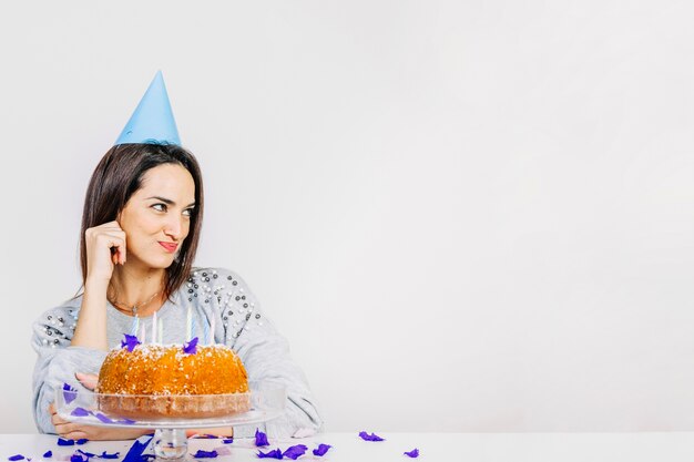 Donna espressiva dietro la torta di compleanno