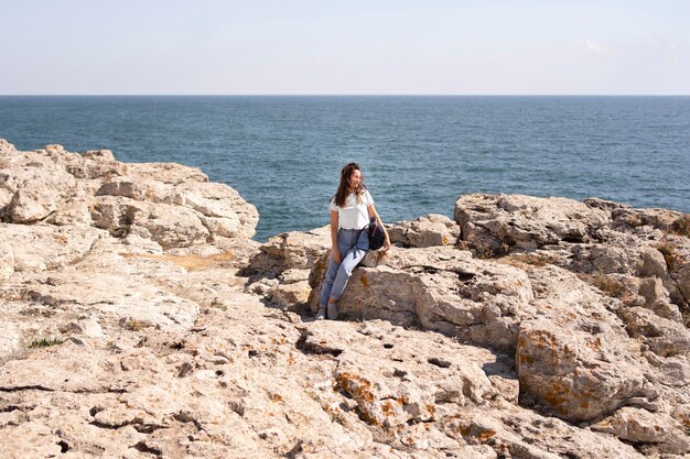 Donna extra lunga del colpo che si siede sulle rocce