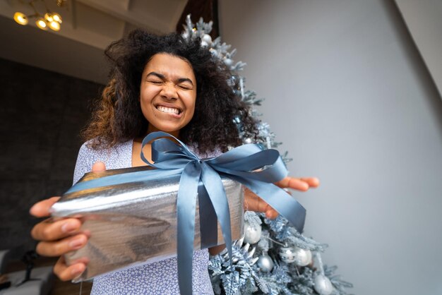 Donna fa un regalo al suo amico nella fotocamera Ritratto di una giovane donna di aspetto afro capelli ricci neri etnici bruna