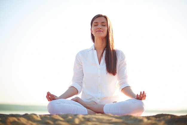 Donna facendo esercizi di yoga sulla spiaggia