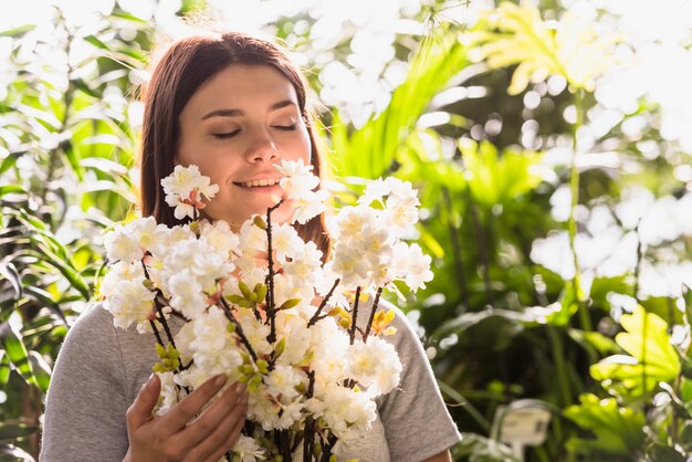 Donna felice attraente che tiene mazzo di ramoscelli di fiori