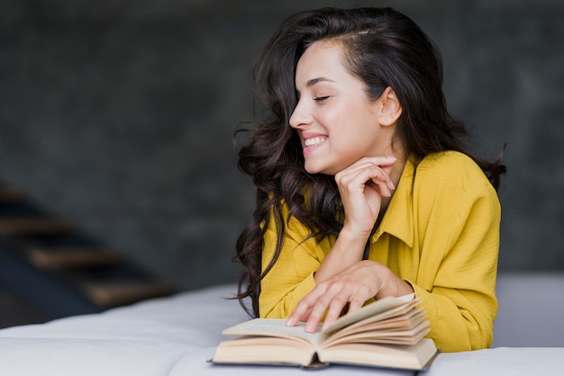 Donna felice castana del colpo medio con il libro