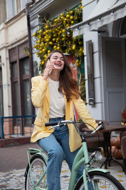 Donna felice che comunica sullo smartphone mentre guida la bici all'aperto