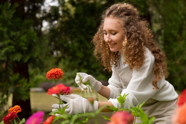 Donna felice che innaffia il fiore, colpo medio