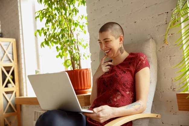 Donna felice che lavora da casa durante la quarantena di coronavirus o COVID-19, concetto di ufficio remoto. Bellissimo modello calvo, manager che svolge attività con laptop, telefono, conferenza online, riunione.