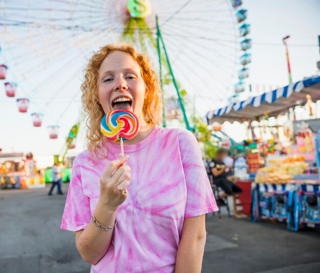 Donna felice che lecca un lecca-lecca al luna park