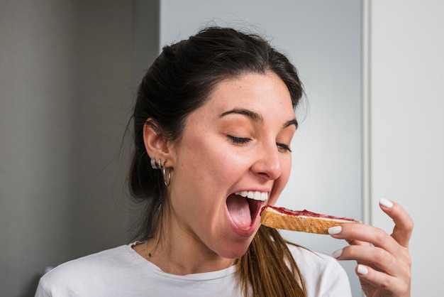 Donna felice che mangia marmellata e pane