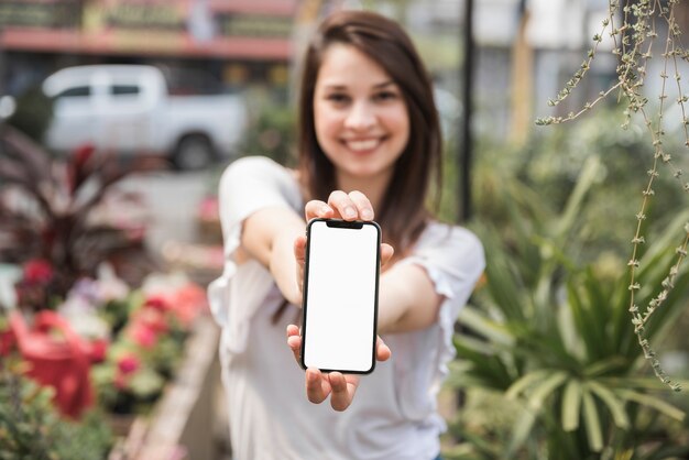 Donna felice che mostra cellulare con schermo bianco vuoto