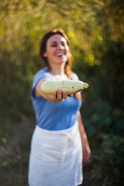 Donna felice che mostra zucca nel campo