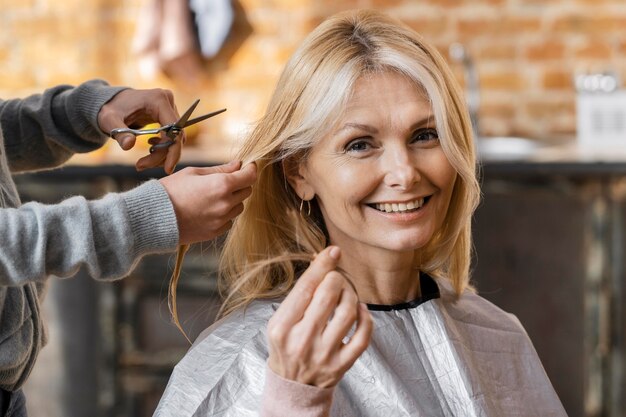 Donna felice che ottiene un taglio di capelli a casa con il parrucchiere