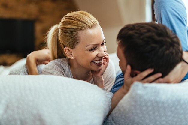 Donna felice che parla con il suo ragazzo mentre ci si rilassa in camera da letto al mattino