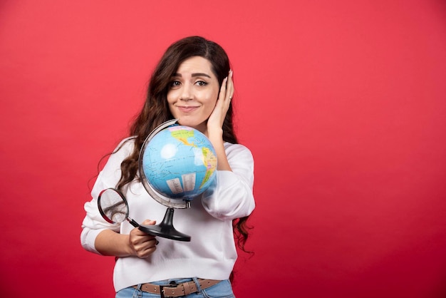 Donna felice che posa con il globo e la lente d'ingrandimento. Foto di alta qualità