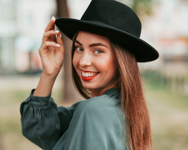 Donna felice che posa con un cappello nero