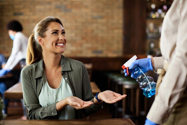 Donna felice che si fa disinfettare le mani in un caffè