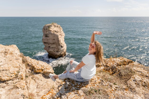 Donna felice che si siede sulle rocce