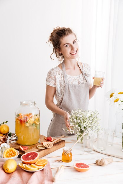 Donna felice che sta all'interno che beve la bevanda dell'agrume