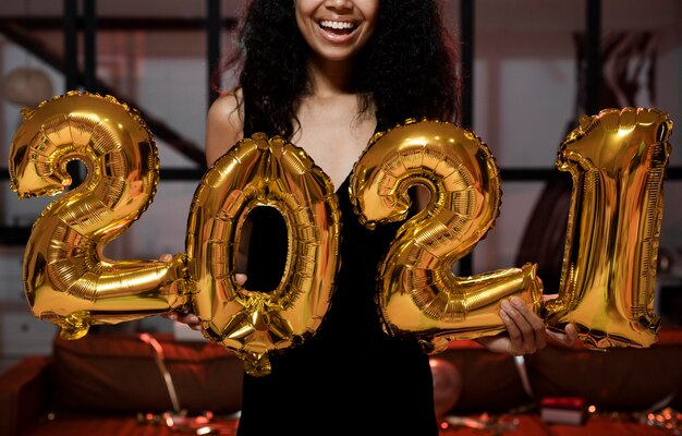Donna felice che tiene 2021 palloncini alla festa